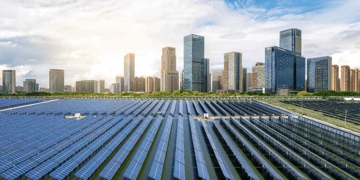Energy Sharing: Solaranlage mit langen Reihen von Photovoltaikmodulen vor einer modernen Stadtsilhouette bei Sonnenlicht.
