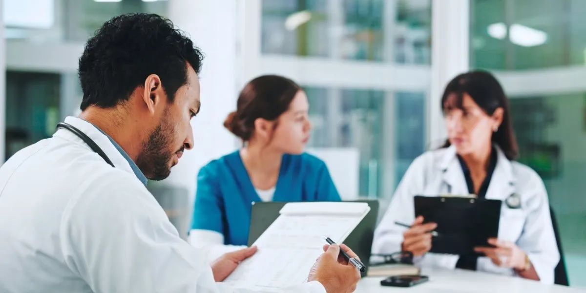 PPR 2.0: Medizinisches Personal plant Personaleinsatz mit Dokumenten in Besprechungsraum eines Krankenhauses