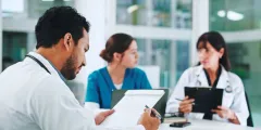 PPR 2.0: Medizinisches Personal plant Personaleinsatz mit Dokumenten in Besprechungsraum eines Krankenhauses