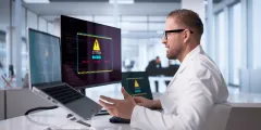 Zero Trust: IT-Sicherheitsexperte vor mehreren Monitoren mit Warnmeldung „System Hacked“ in einem modernen Büro.